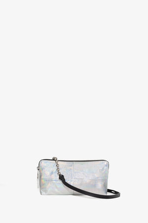 Kleine, rechteckige, silberfarbene Hologramm-Clutch von INA KENT mit einem schwarzen, abnehmbaren Handgelenkriemen, Reißverschluss und minimalistischem Design, vor einem schlichten weißen Hintergrund.