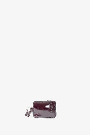Small, rectangular burgundy leather pouch with a zipper and attached keyring from INA KENT, placed against a plain white background.