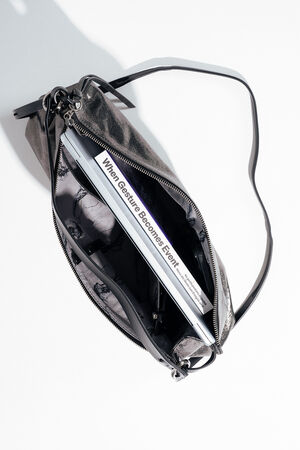 A black leather INA KENT bag with a zipper is open, revealing a book titled “When Gesture Becomes Event” inside.