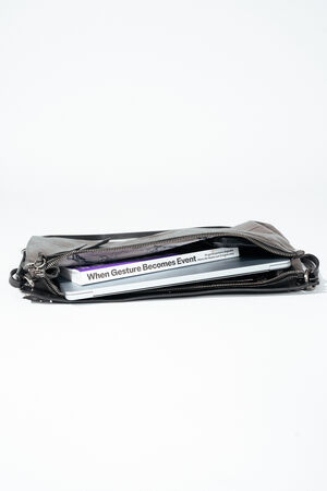 A partially unzipped black leather INA KENT bag with a book titled “When Gesture Becomes Event” visible inside, placed on a white background.