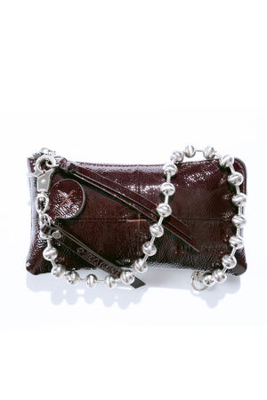 A dark burgundy leather zippered clutch by INA KENT, featuring visible stitching and a chunky silver beaded chain handle, lays on a white background.