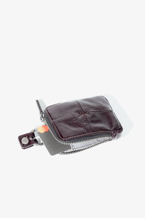 A small, dark brown leather zippered wallet by INA KENT with a card partially visible inside, set against a plain white background.