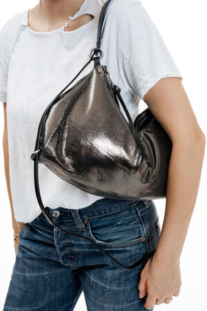 Person wearing a white t-shirt and blue jeans, carrying a large metallic silver INA KENT handbag over their shoulder.