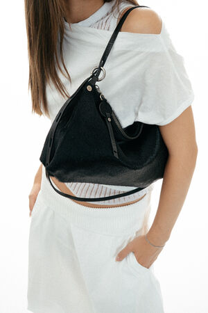Woman in white outfit carrying a large black INA KENT shoulder bag, shown from shoulders to knees against a plain white background.