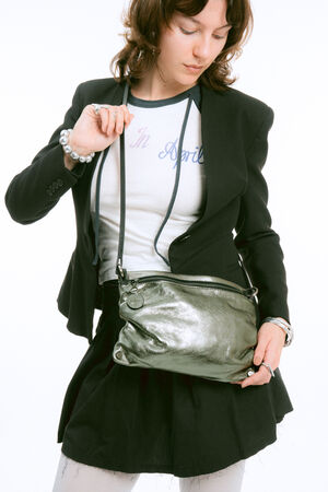A person in a black blazer and white graphic t-shirt wears a metallic silver crossbody bag.