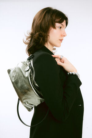 A person wearing a black blazer and a metallic silver backpack.