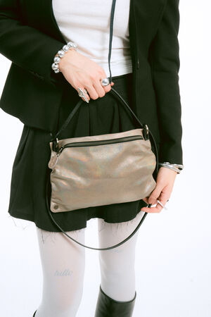 A person in a black blazer and skirt holds a shimmering metallic shoulder bag.