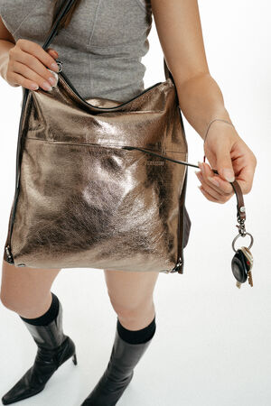 A metallic bronze INA KENT hobo-style shoulder bag worn by a person.