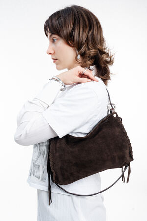A person in a white shirt wearing a brown suede INA KENT hobo bag over their shoulder.
