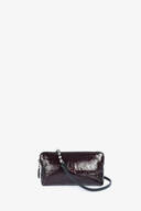 A small, rectangular, dark burgundy INA KENT leather clutch bag with a black strap and metal bead detail, displayed against a plain white background.