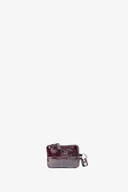 A small, glossy dark brown INA KENT pouch with a zipper and a metal keychain attachment, centered on a plain white background.